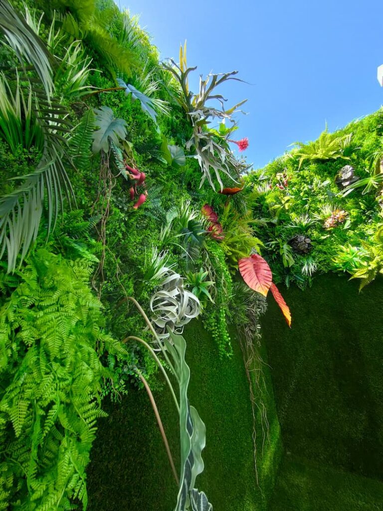 Detalle de un jardín vertical con flores y follaje variado visto desde abajo